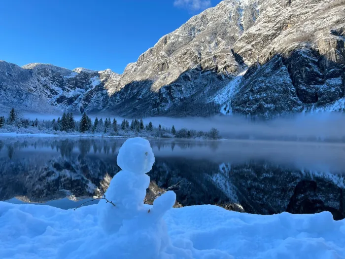 Snežak ob bregu Bohinjskega jezera, v ozadju gore